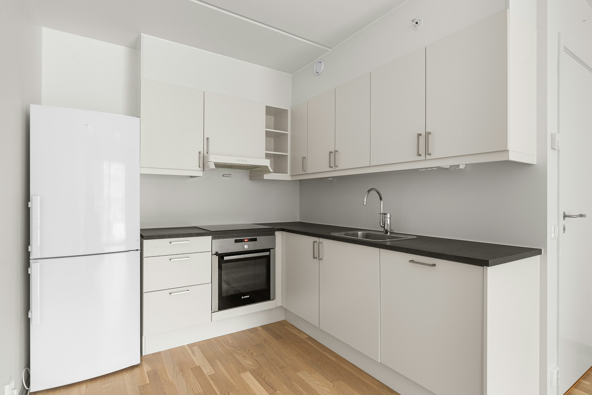 A kitchen with white cabinets and black counter tops